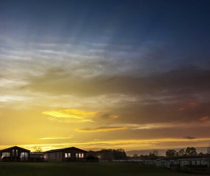 Sunset over the luxury holiday lodges at Arrow Bank Country Holiday Park